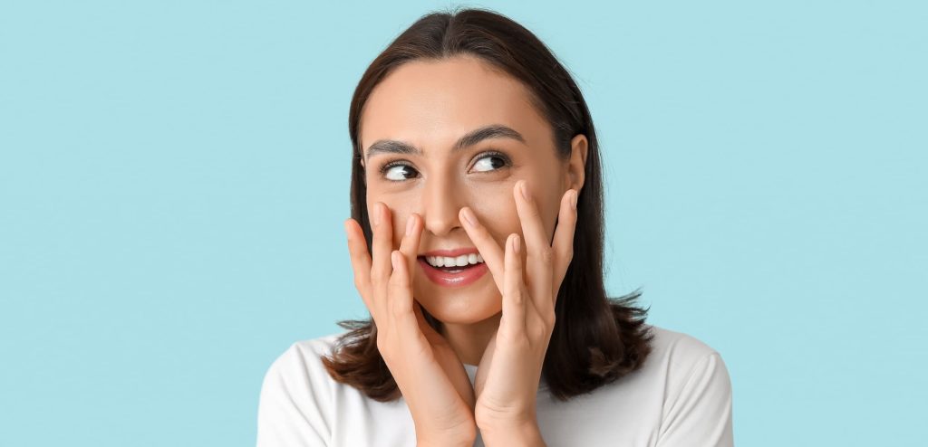 Femme souriante appliquant une crème hydratante sur son visage