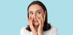 Femme souriante appliquant une crème hydratante sur son visage